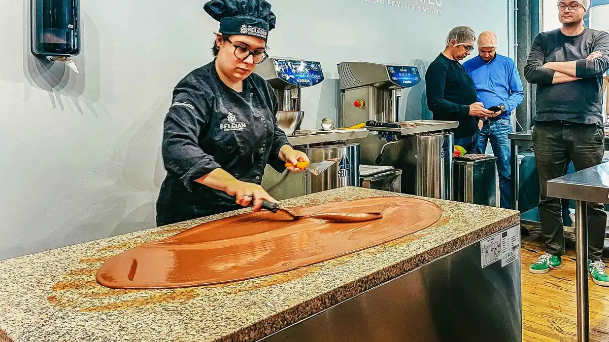 Chocolate maker pouring dark chocolate in a bean-to-bar chocolate workshop, one of the chocolate tours in Brussels