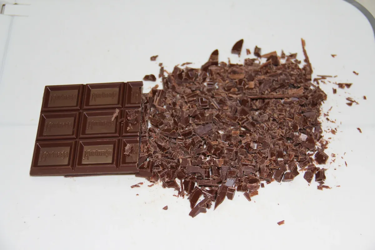 Chopped dark chocolate beside a bar, the first step of a chocolate workshop on chocolate tours in Brussels